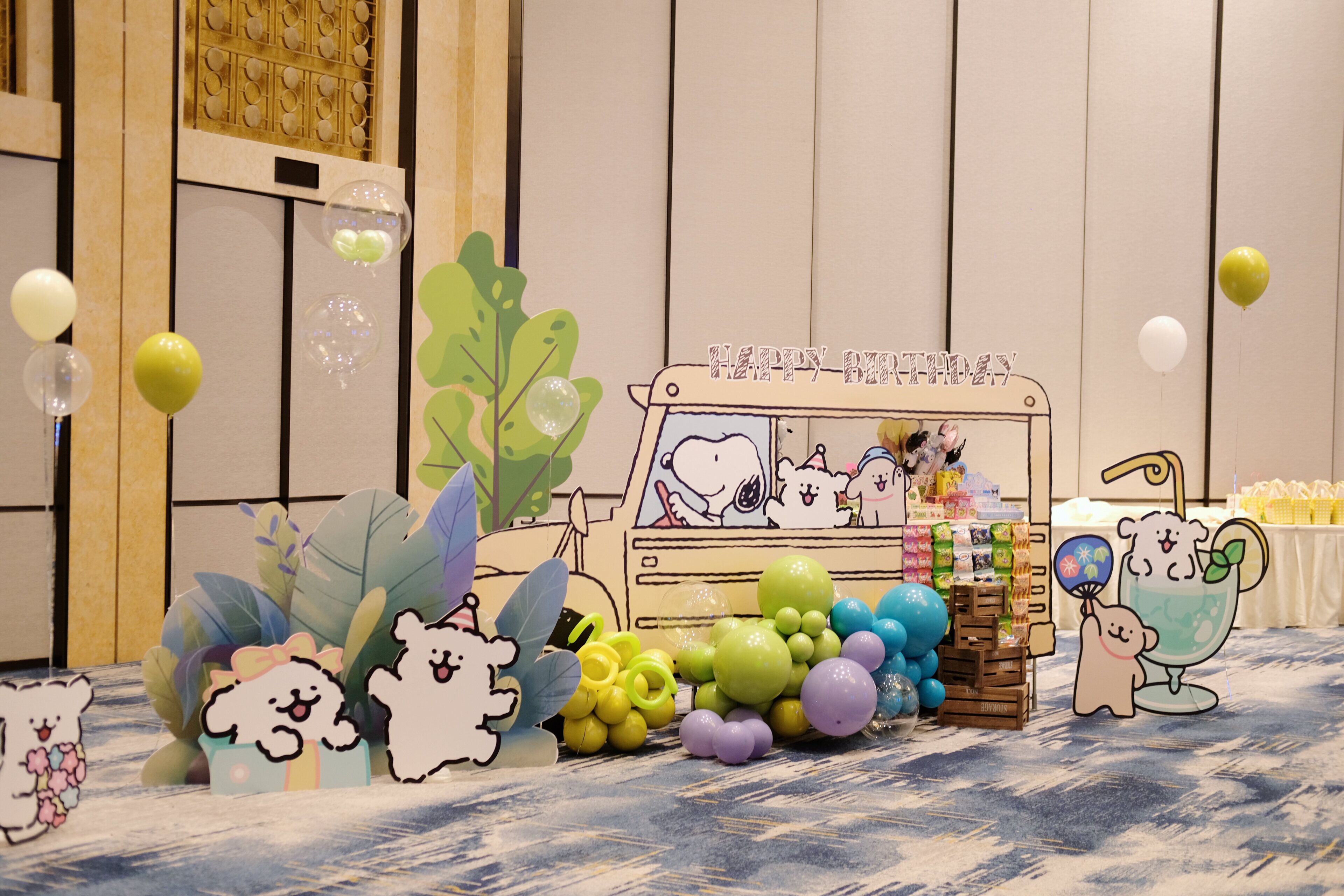 A room with a table decorated for a birthday party, featuring balloons, a cake, and a 'Happy Birthday' sign.