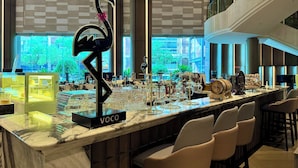 Un área de bar con encimera de mármol, una escultura de flamenco negro y varios vasos.