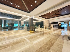 Eine großzügige Lobby mit Marmorboden, einem Empfangstresen und einer großen, dekorativen Elefantenstatue.
