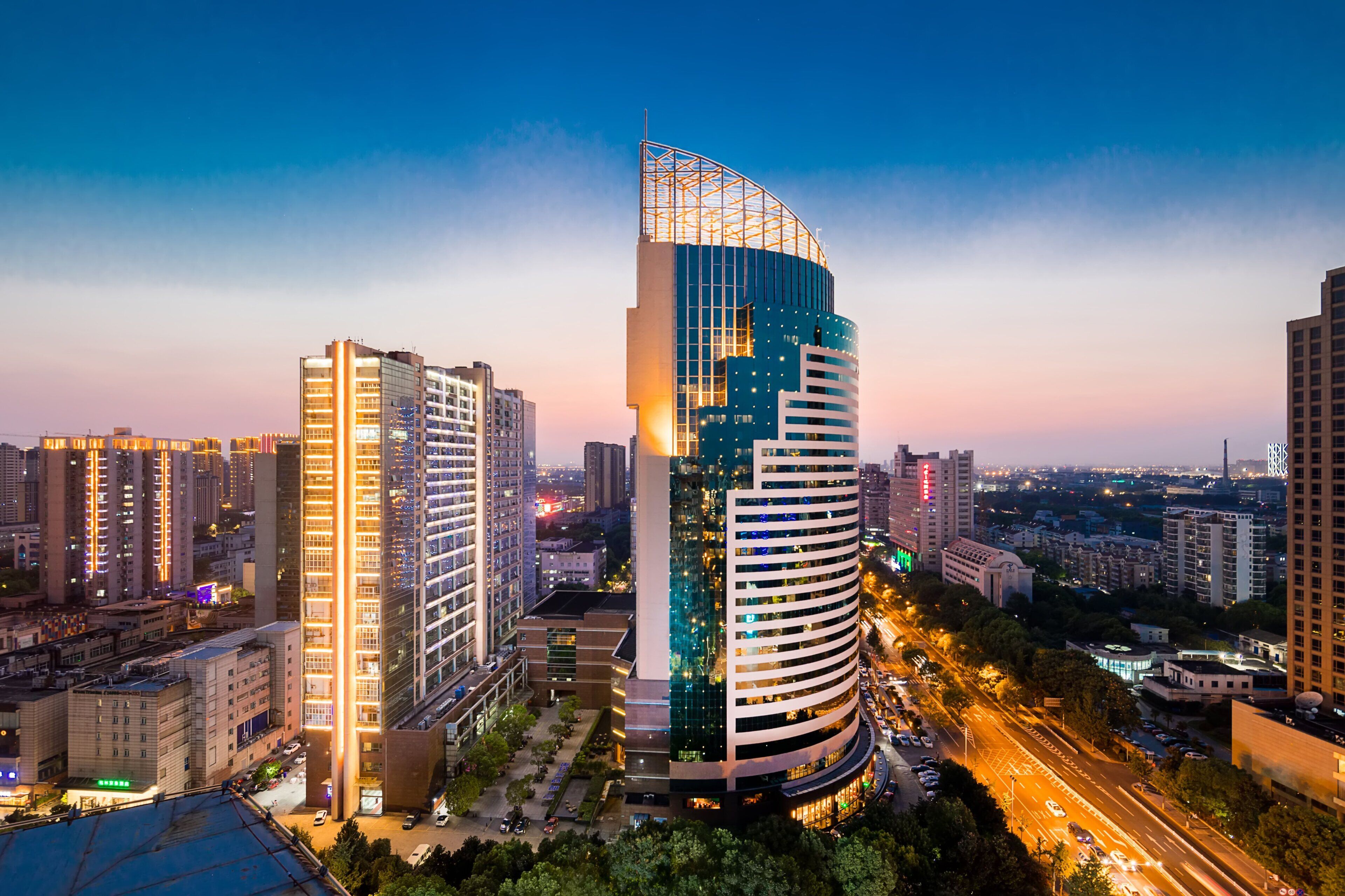 Un edificio alto con un diseño curvo único, rodeado de otros edificios altos en un entorno urbano.