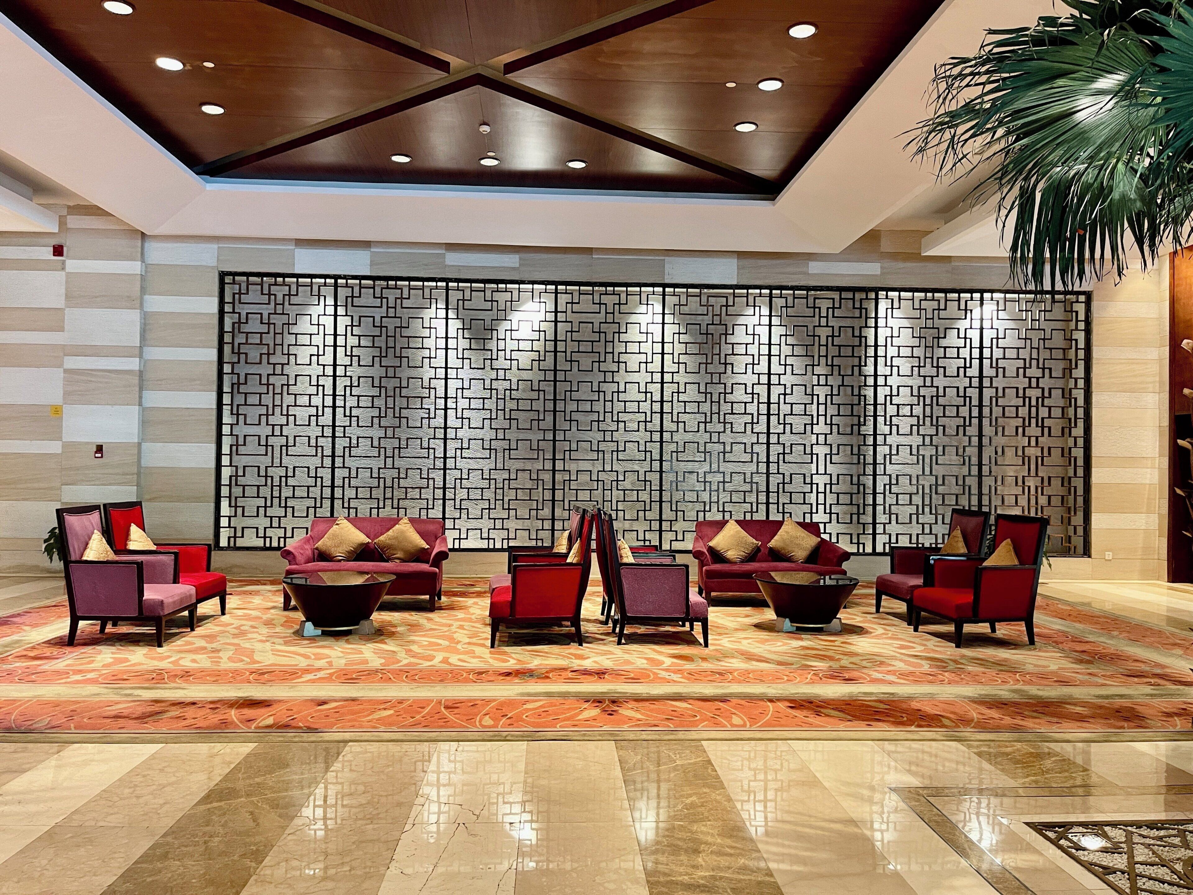 A lobby with a patterned wall, red seating, and a polished floor.