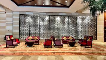 A lobby with a patterned wall, red seating, and a polished floor.