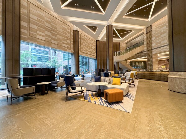 A spacious lobby with a high ceiling, modern furniture, and a view of the outside. - voco Changzhou Fudu by IHG (Changzhou)