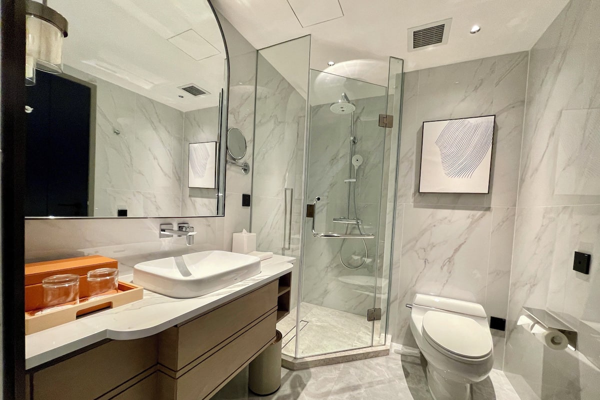 Un baño moderno con ducha envuelta en vidrio, un lavabo blanco y un inodoro.