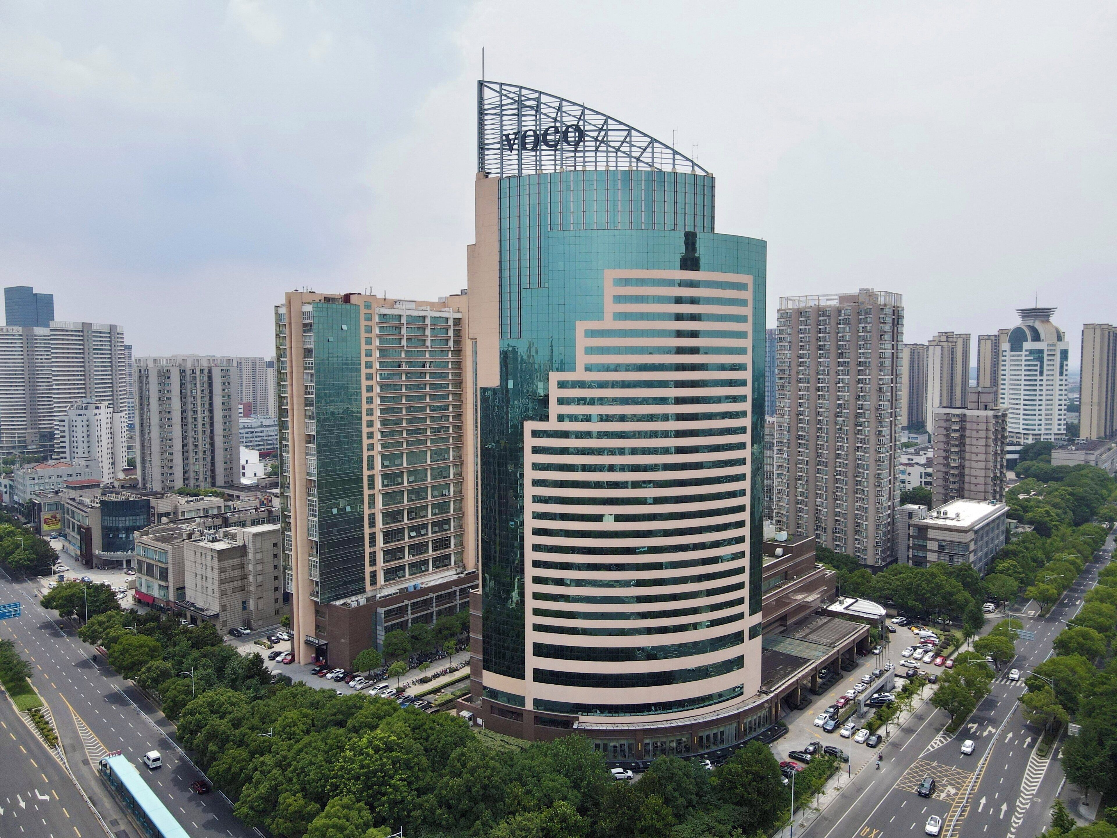 Un edificio de gran altura con fachada de vidrio curvo y un llamativo letrero 'VOGO' en la parte superior.
