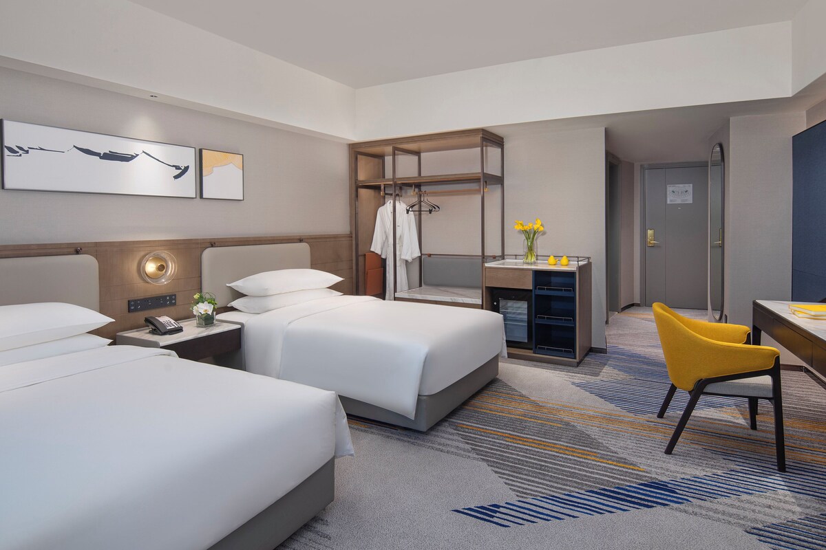 Une chambre d’hôtel avec deux lits, un bureau, une chaise, une coiffeuse et une salle de bain.