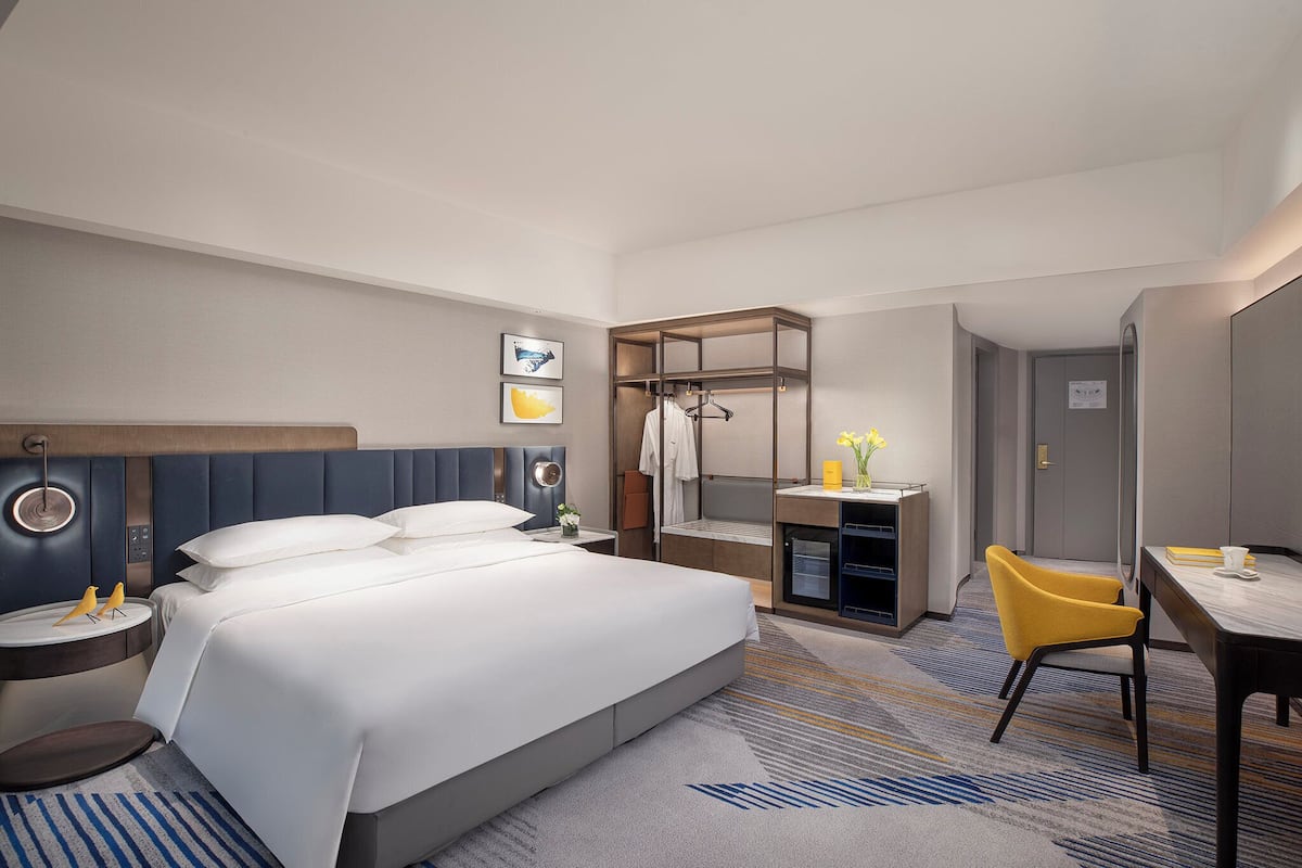 Habitación de hotel con cama, mesitas de noche, escritorio, silla y armario.