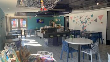 Un café moderne doté d’un bar central, de plusieurs espaces de détente et d’une variété de magazines à la disposition des clients.