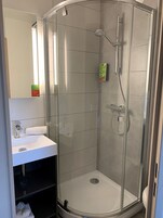 Un baño moderno con ducha de vidrio, un lavabo blanco y un espejo.