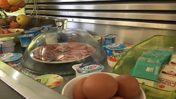 A kitchen counter with various food items including a plate of sliced meat, a bowl of eggs, and several containers of yogurt.