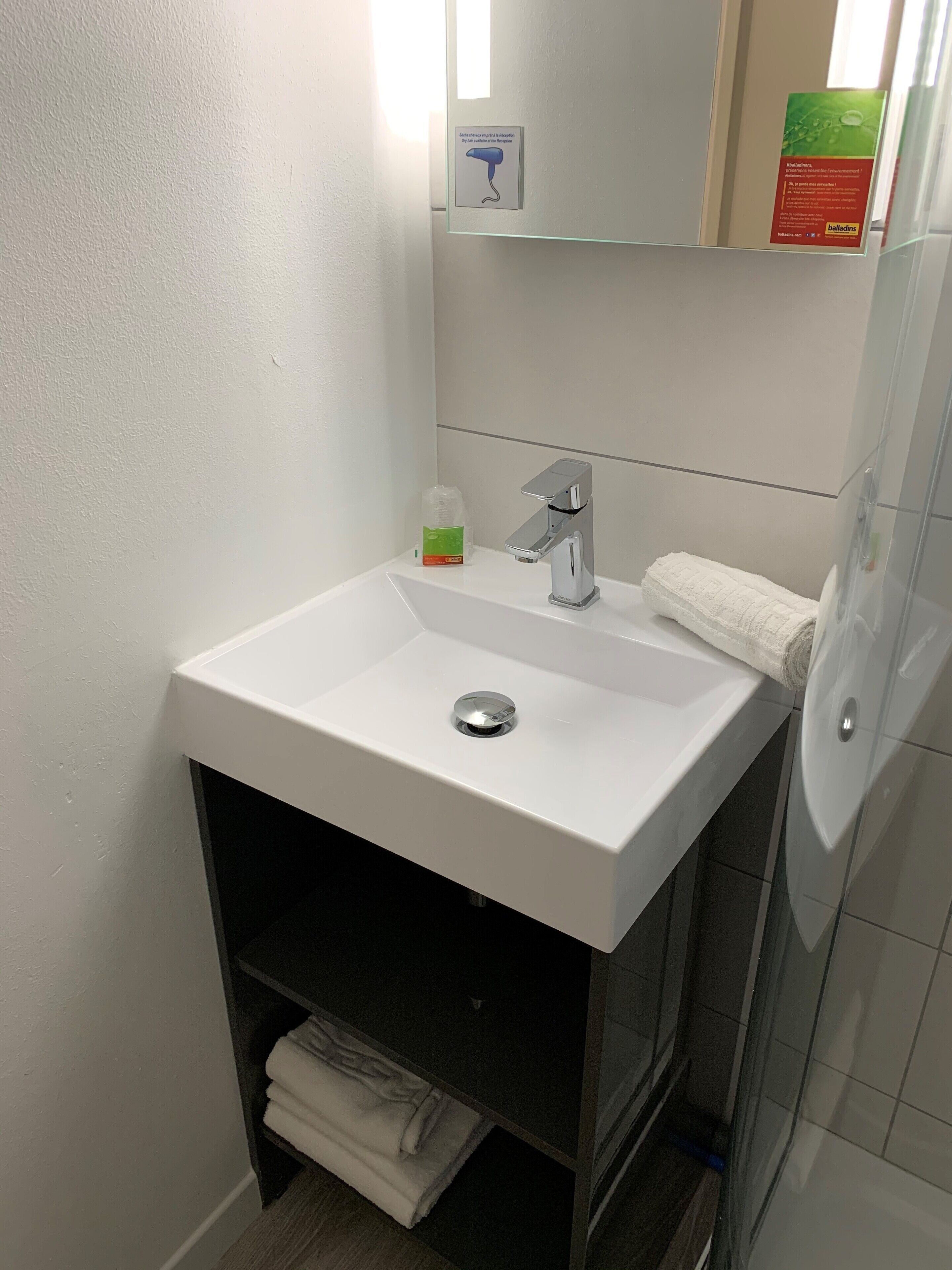 A bathroom with a white sink, a mirror, and a towel rack.