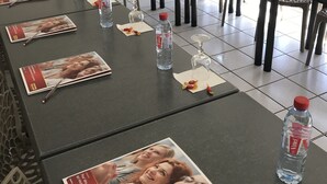 A conference room with tables set for meetings, water bottles, magazines, and a coffee machine. - Brit Hotel Essentiel Tours Sud – Chambray-lès-Tours  (Chambray-les-Tours)