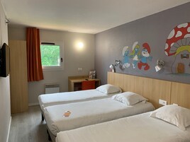Habitación de hotel con dos camas, un escritorio, una silla, una ventana con cortinas y una pared decorada con personajes de dibujos animados.