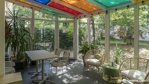 A sunroom with a glass ceiling, a dining table, chairs, and potted plants. -  BIG MAMA Leipzig (Leipzig)