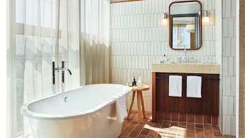 Un baño moderno con una bañera independiente, un mueble de tocador de madera, un espejo y un perchero para toallas.