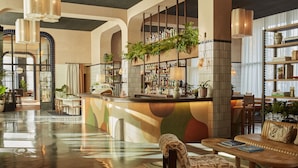 A spacious lobby with a bar area, seating arrangements, and a variety of plants.