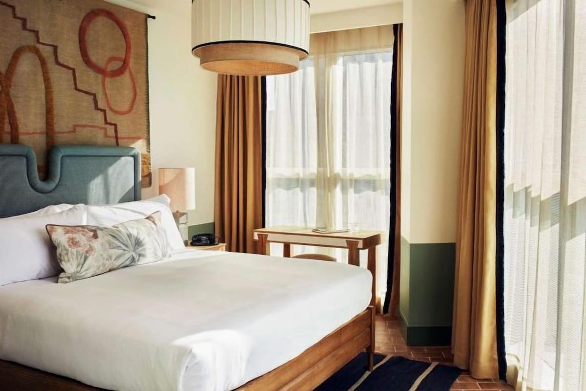 Camera d'albergo con un letto grande, una scrivania e una finestra con tende.