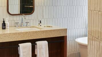 A bathroom with a wooden vanity, two sinks, a mirror, and a toilet.