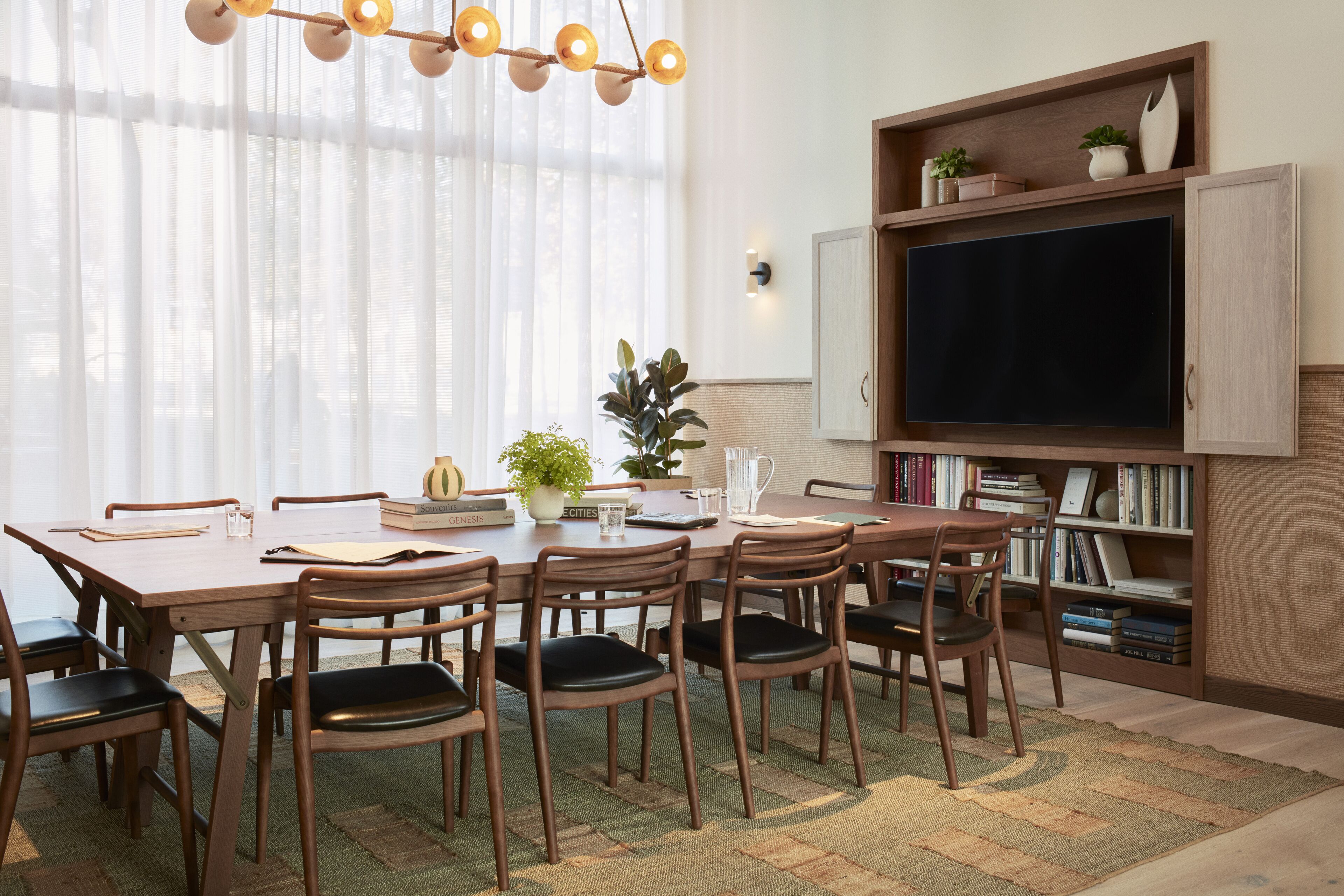 A dining area with a wooden table and chairs, a bookshelf, and a television.