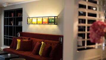A modern living room with a red sofa, a small table, and a bookshelf.