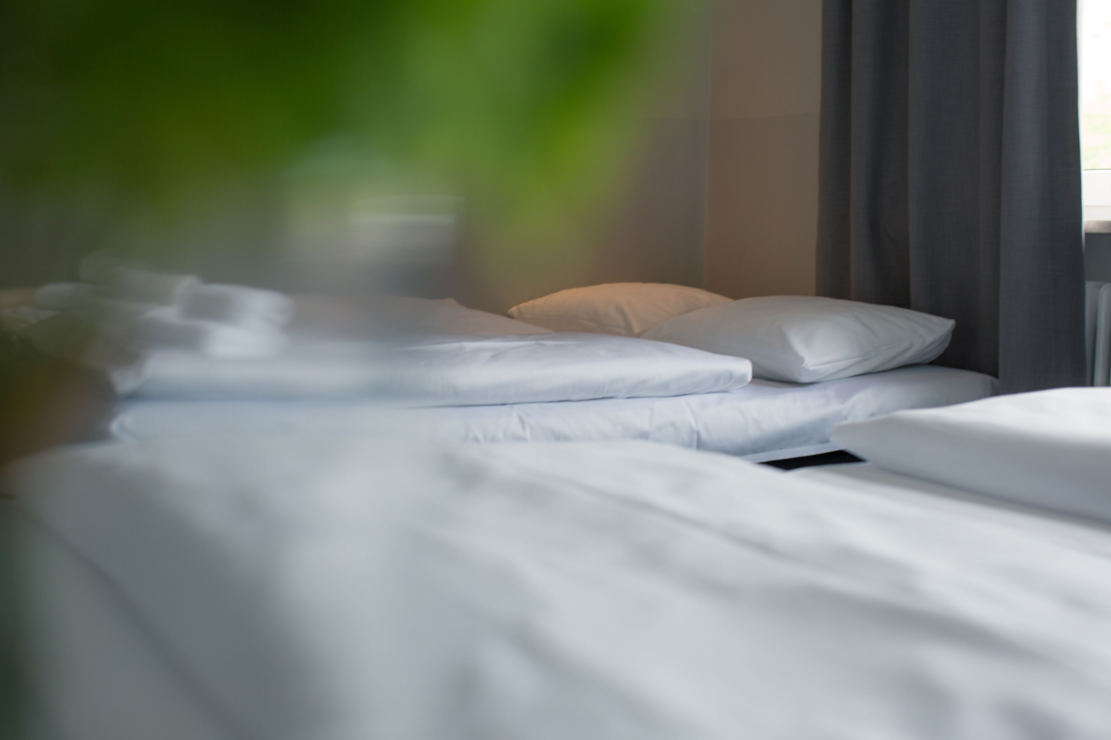 Ein Bett mit weißen Laken und einem Kopfkissen.