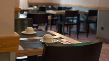A dining area with tables and chairs, a white cup and saucer on one table, and a menu on the table.