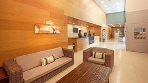 Un'area della hall di un hotel con una reception, due divani, un tavolino da caffè e una parete in legno.