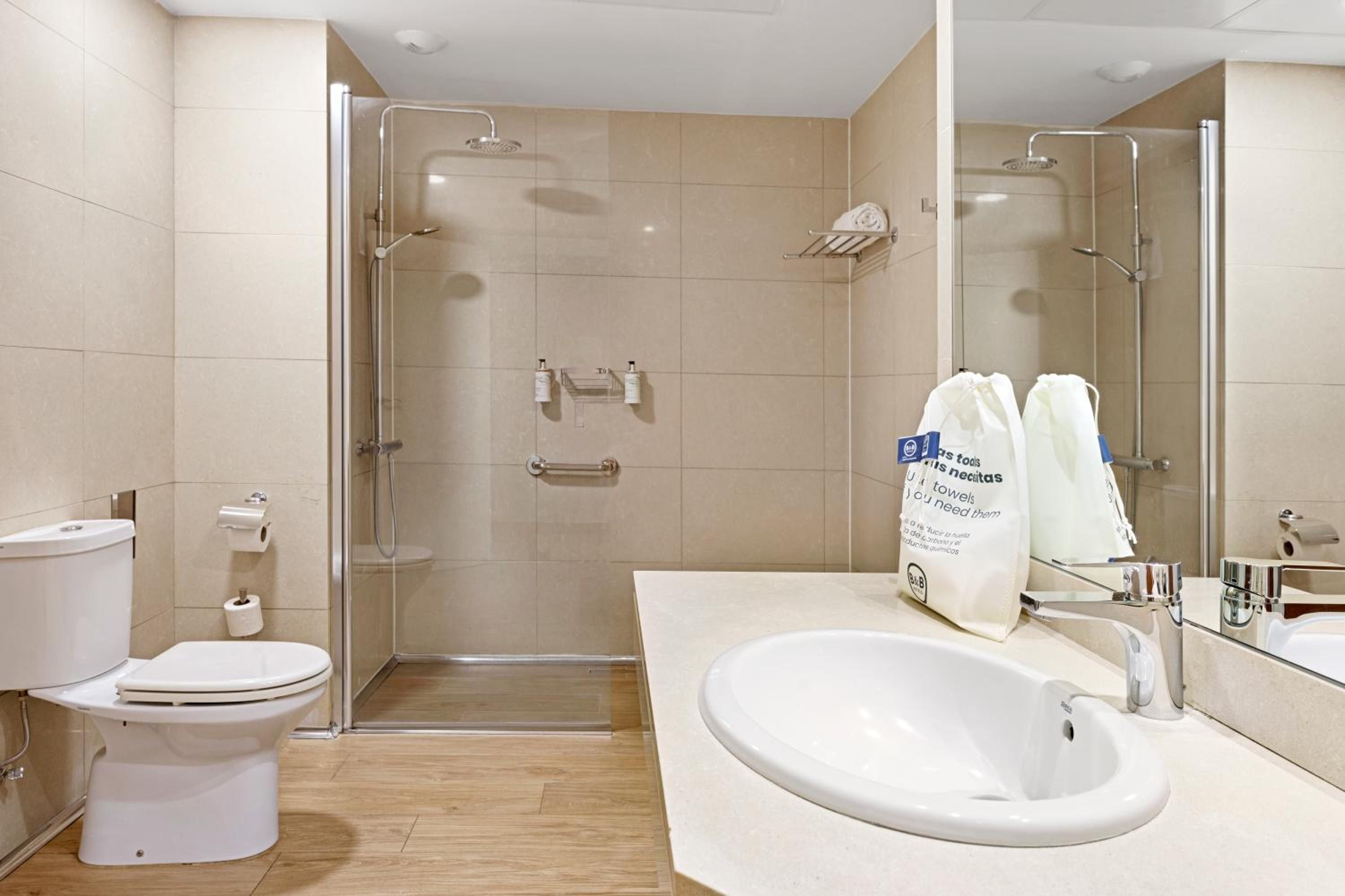 A modern bathroom with a glass-enclosed shower, a white toilet, and a sink with a mirror.