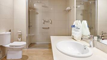 A modern bathroom with a glass-enclosed shower, a white toilet, and a sink with a mirror.