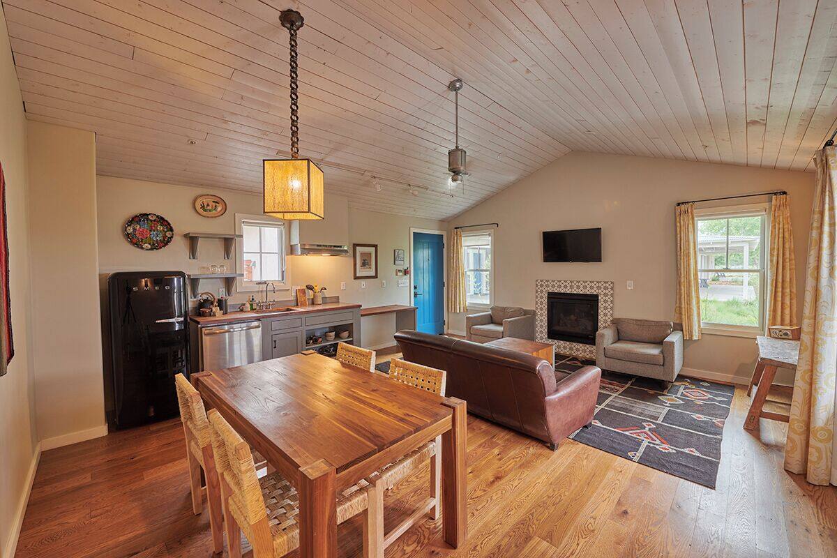 A spacious living area with a wooden dining table, leather sofa, and a fireplace.
