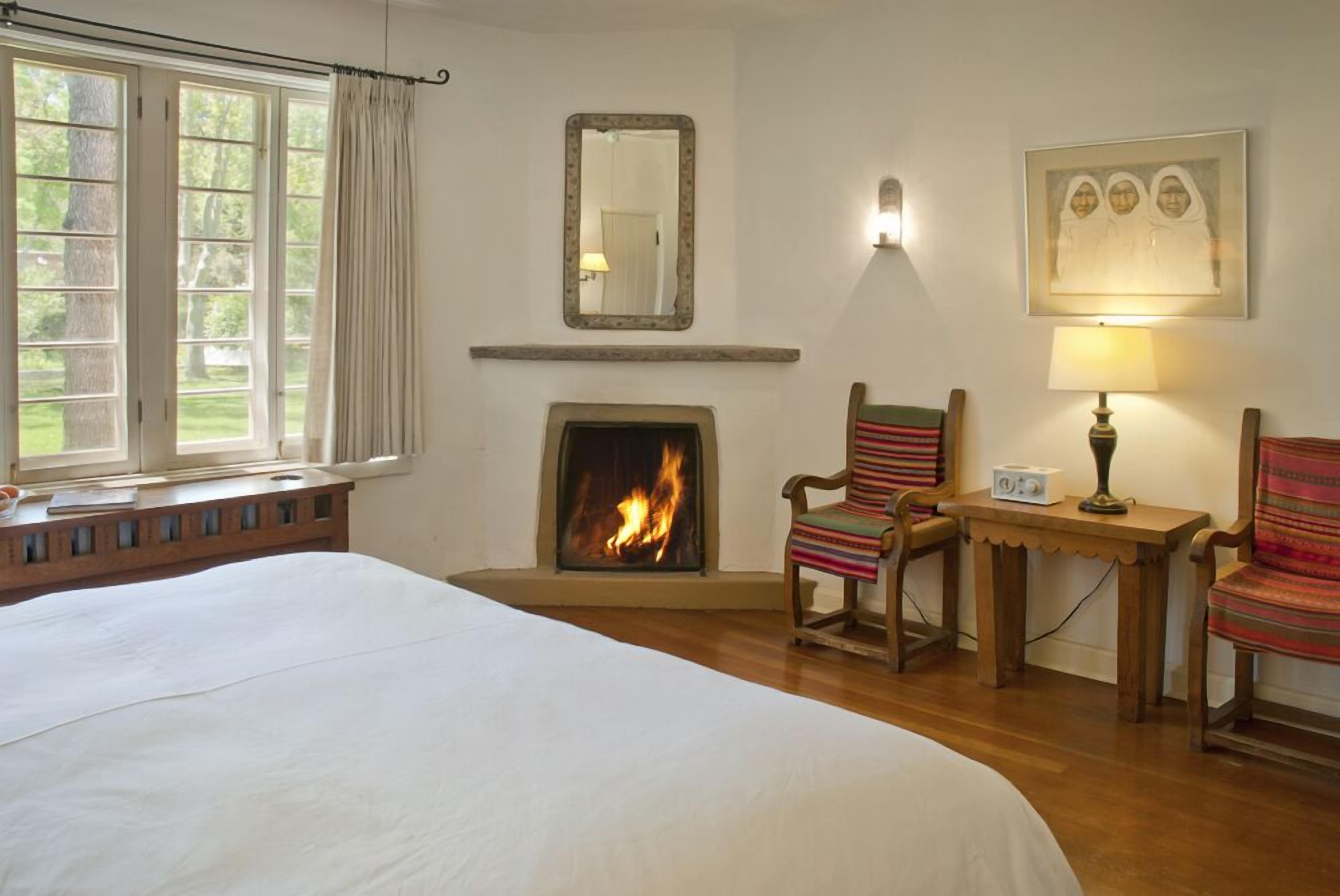 A room with a fireplace, a bed, a chair, and a table.