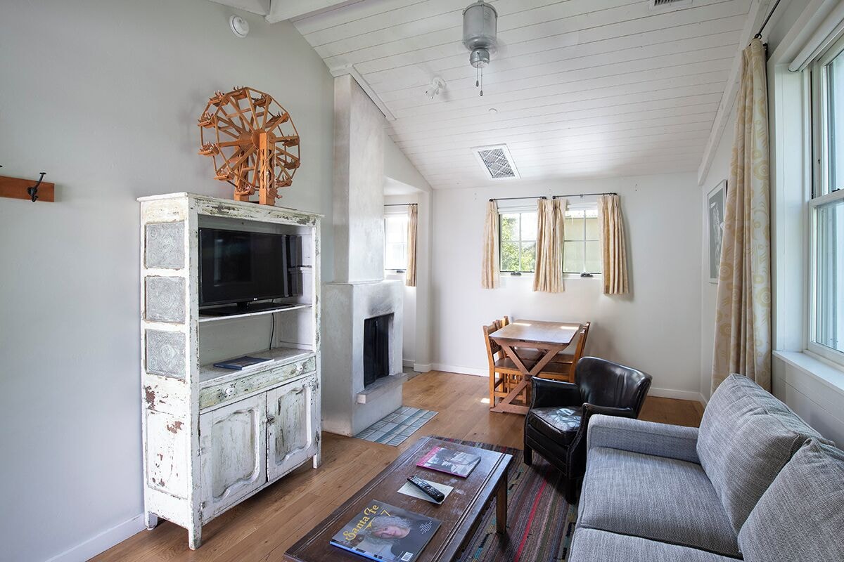 A living room with a white cabinet, a fireplace, a television, a sofa, and a dining table.