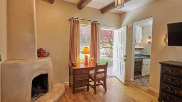 A room with a fireplace, wooden desk, chair, and a television mounted on the wall.