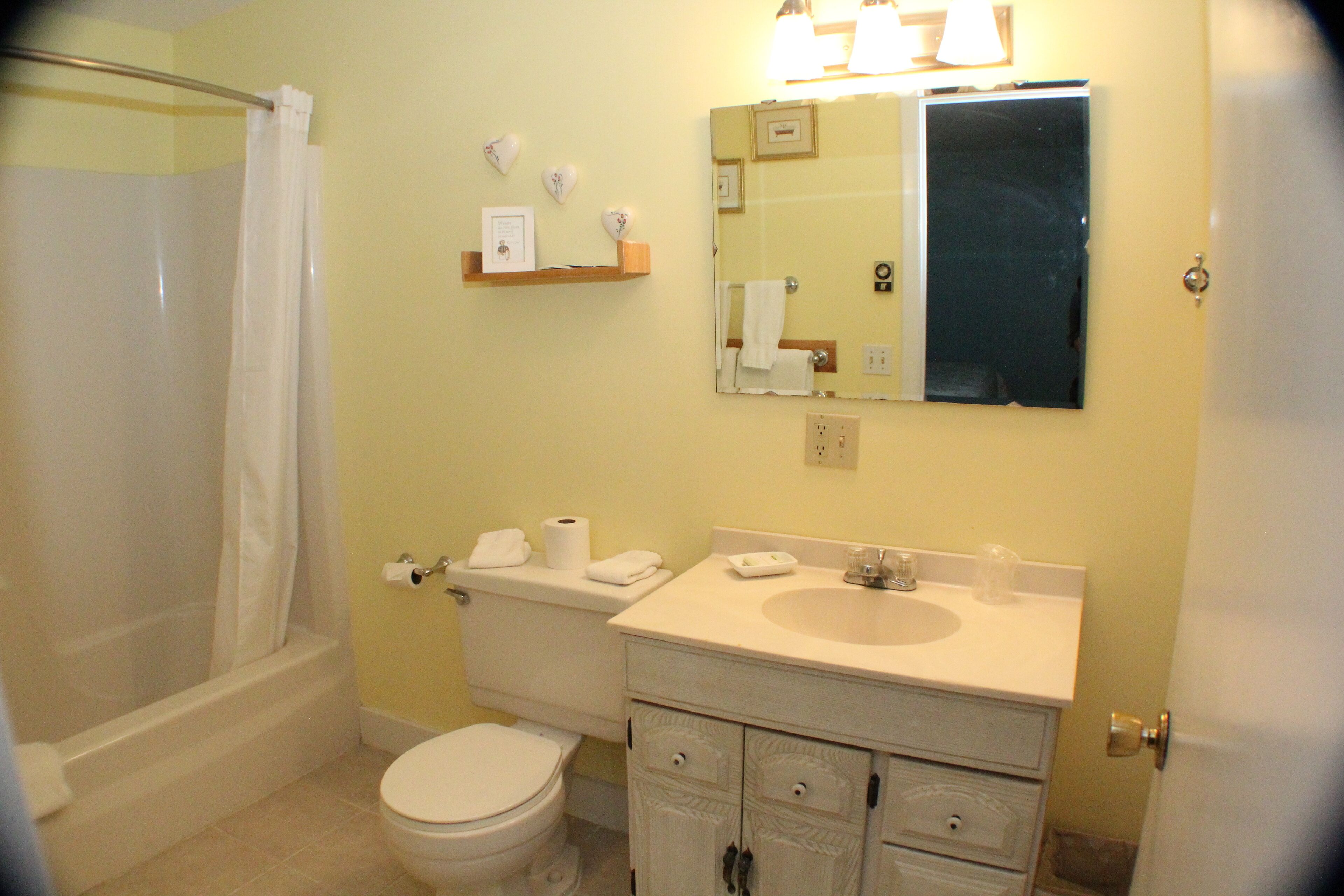 A bathroom with a bathtub, toilet, sink, and vanity.