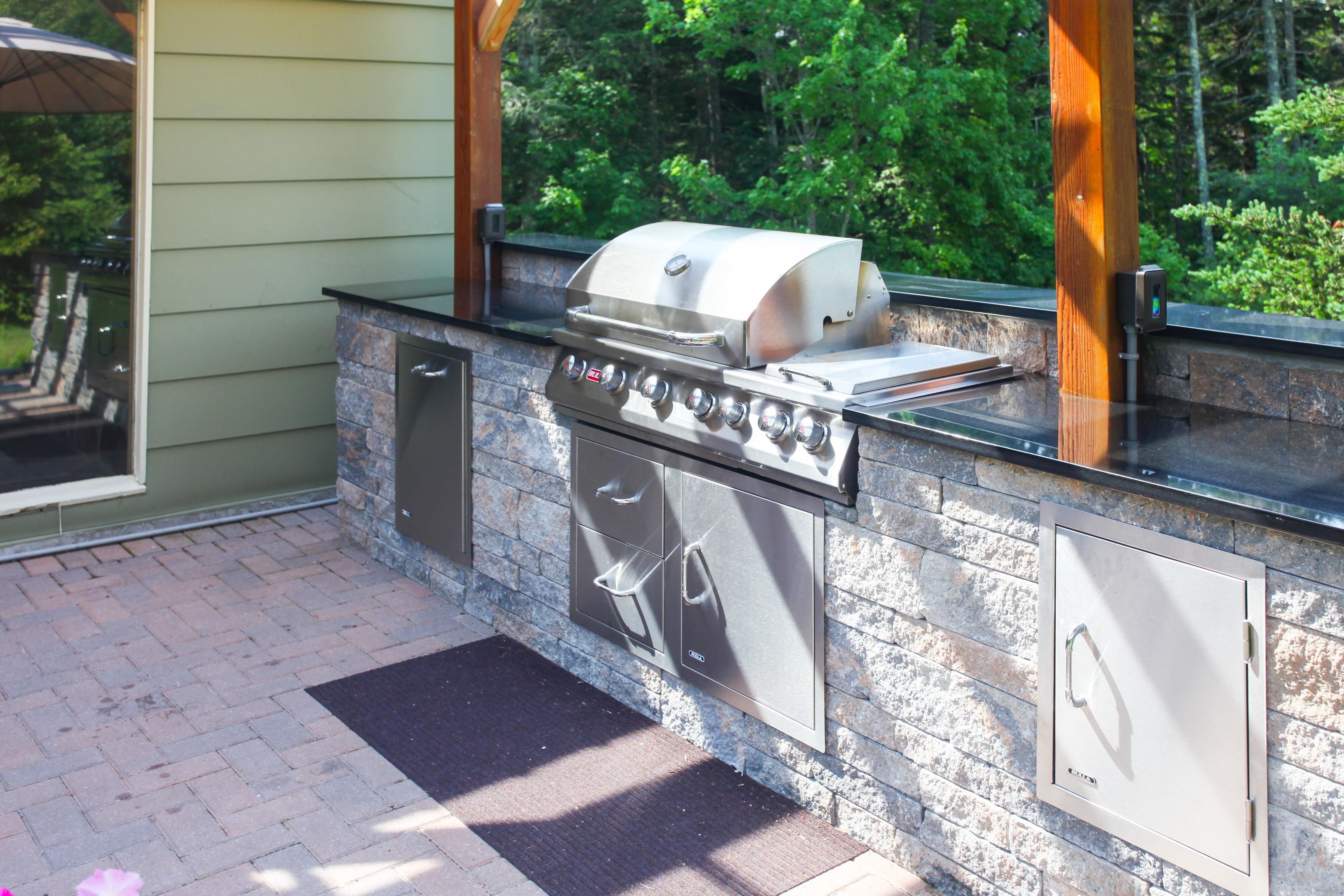 An outdoor kitchen with a built-in grill, oven, and storage cabinets.