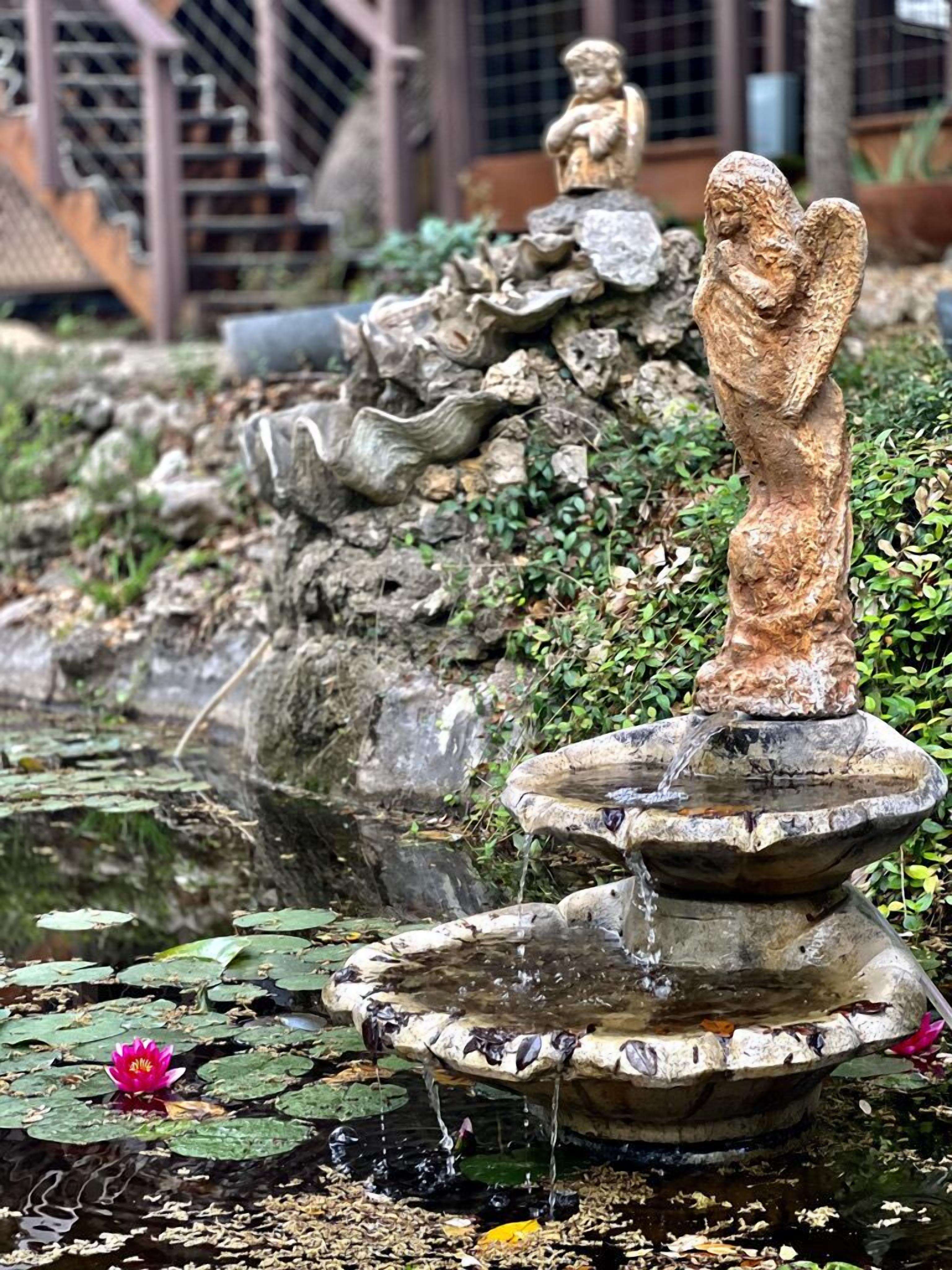 A stone fountain with water flowing, surrounded by rocks and greenery.