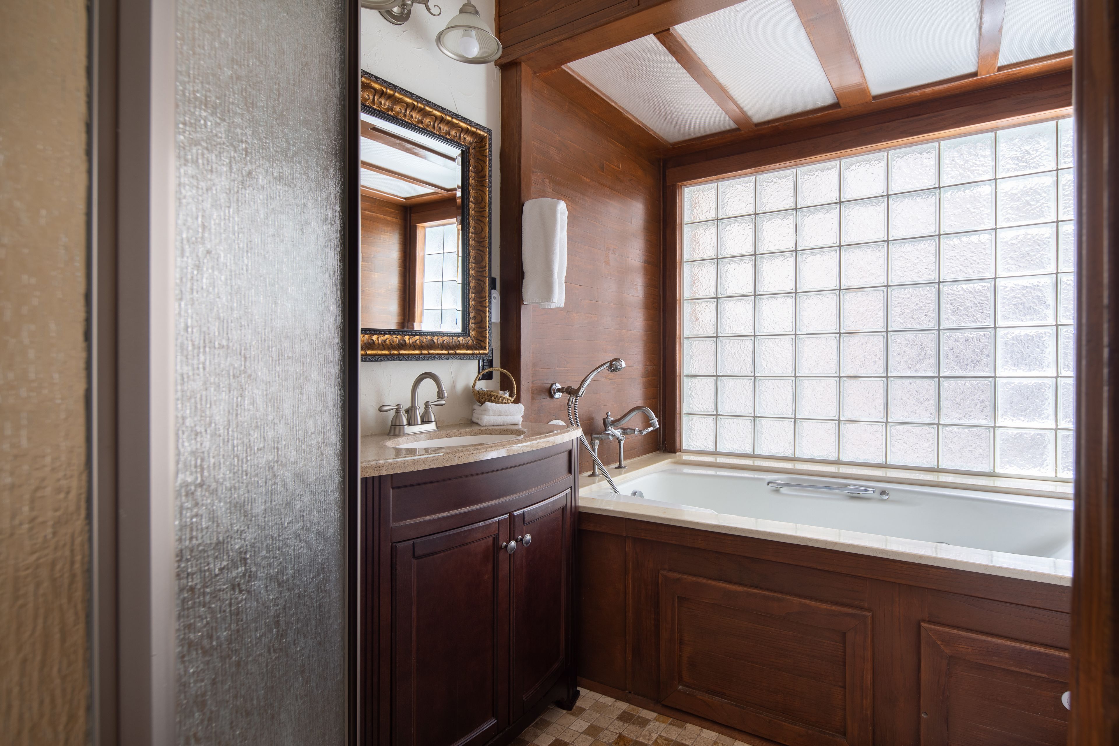 A bathroom with a large window, a sink, and a mirror.