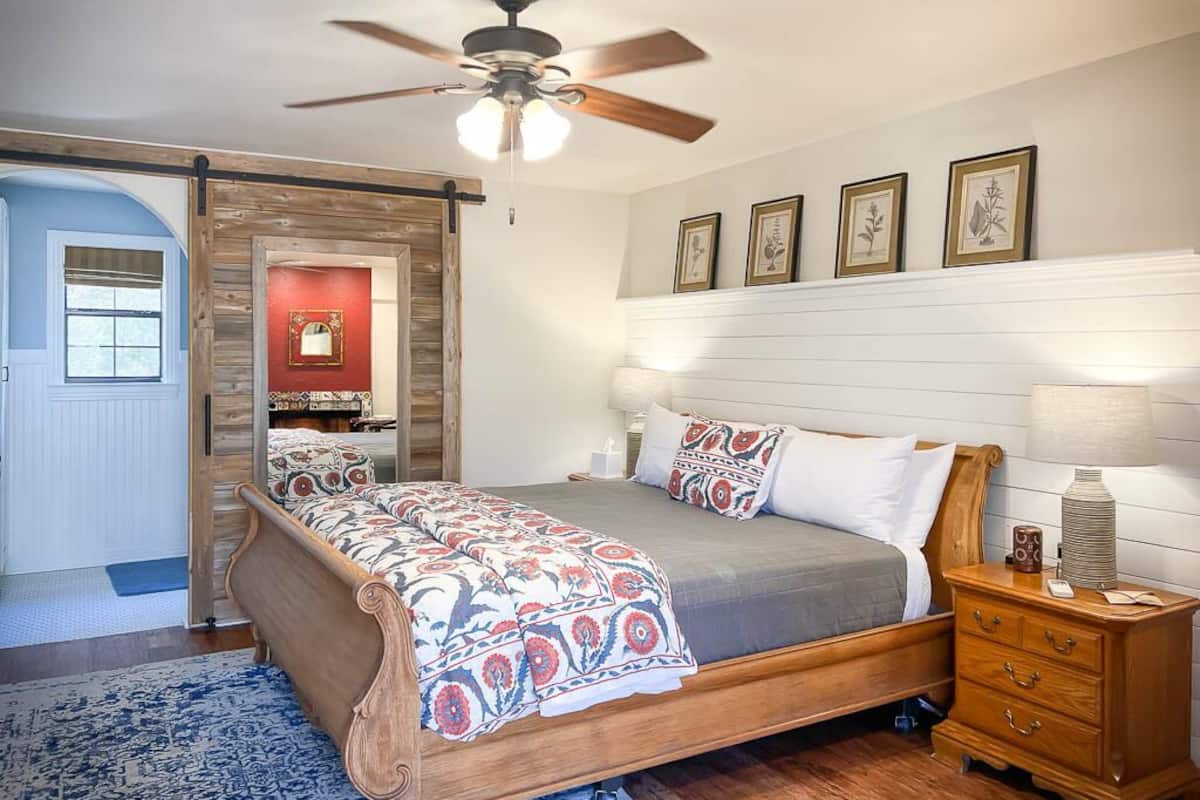 A bedroom with a bed, wooden nightstand, and a ceiling fan.