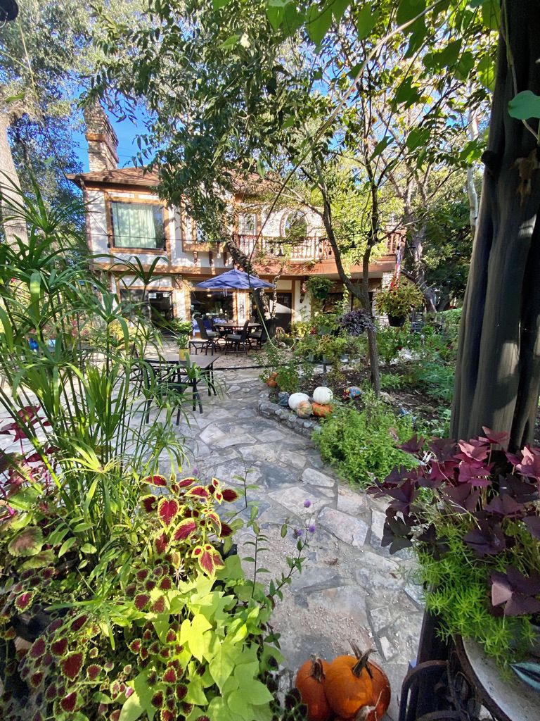 A stone pathway leading to a building with outdoor seating.