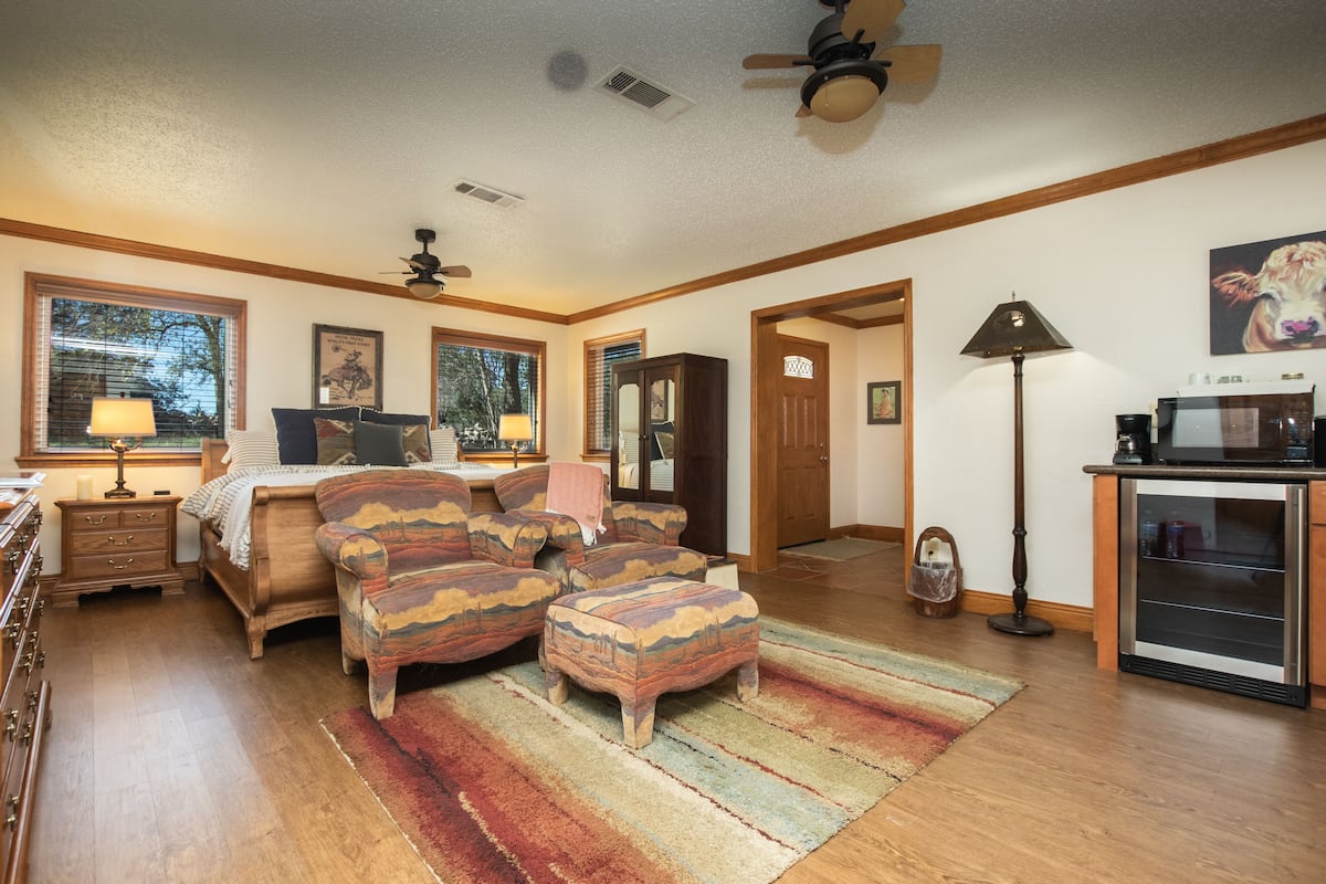 A bedroom with a bed, a dresser, a nightstand, a lamp, a ceiling fan, and a window.
