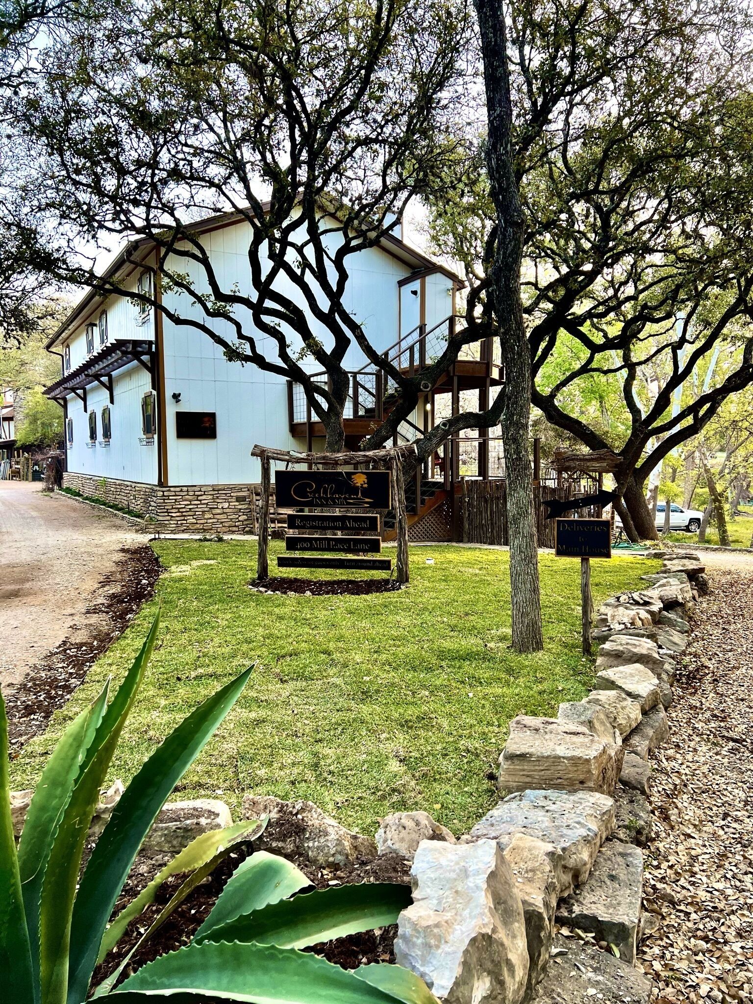 A white building with a stone foundation, a wooden deck, and a sign indicating 'Registration Ahead'.