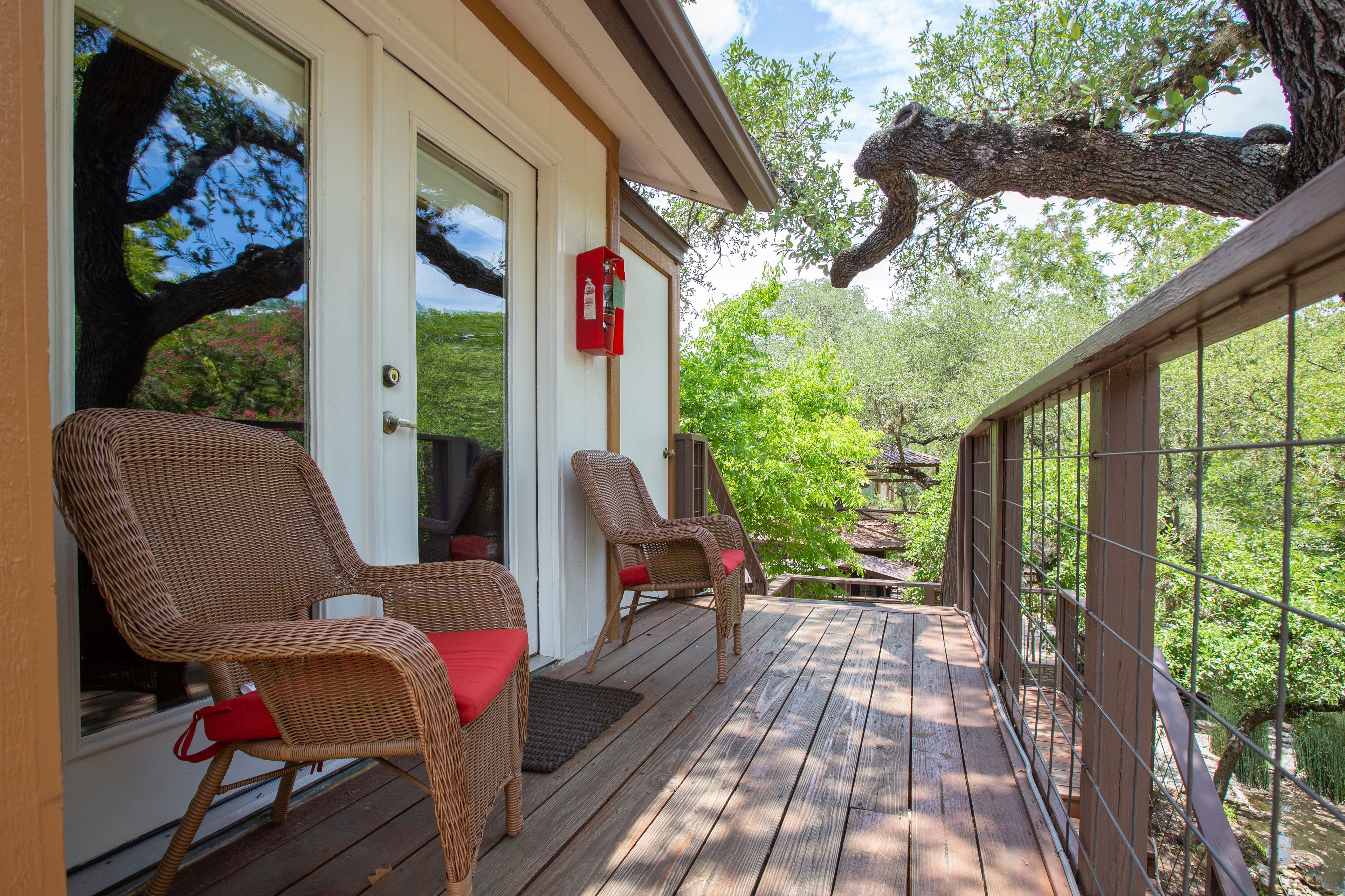 Une terrasse en bois avec des chaises en osier et une boîte aux lettres rouge.