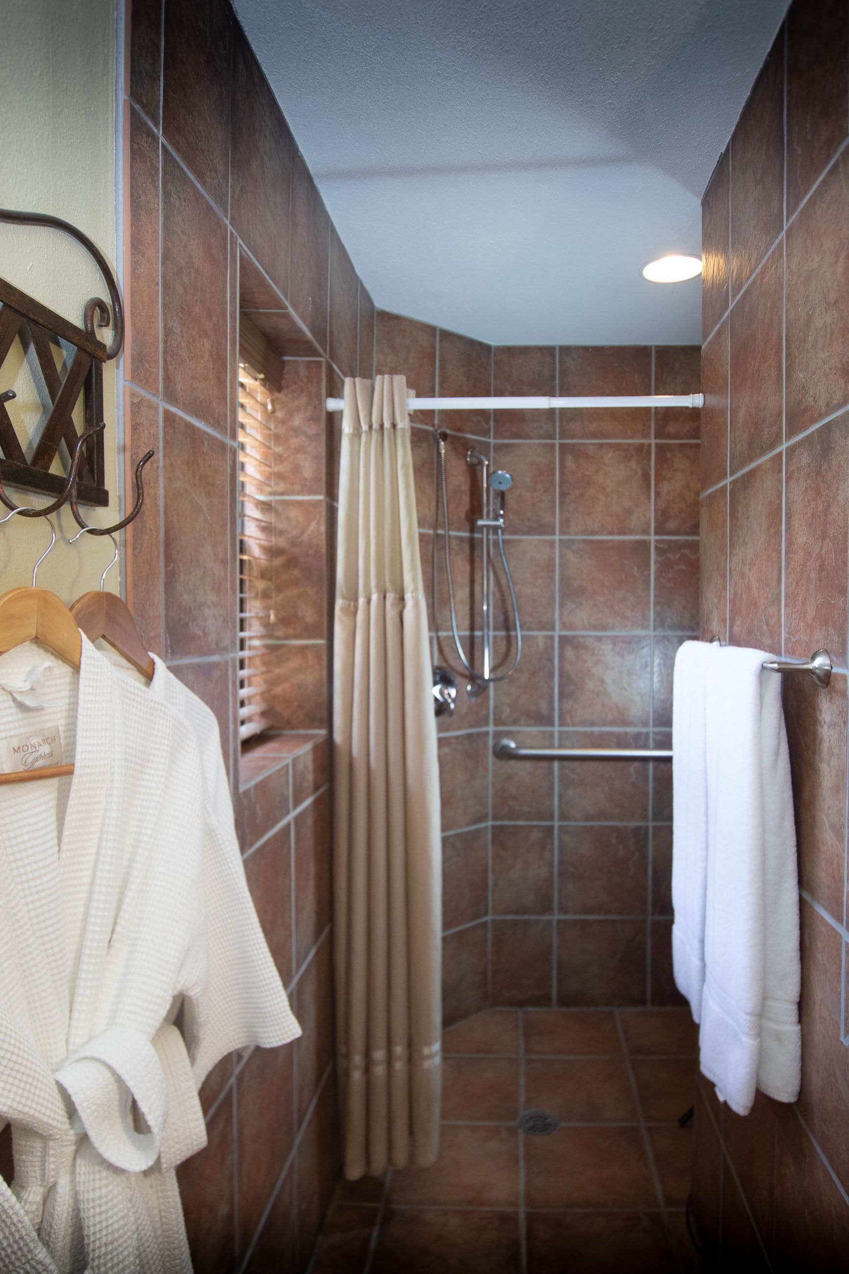 A shower stall with a glass door, a towel rack, and a towel hanging on the wall.