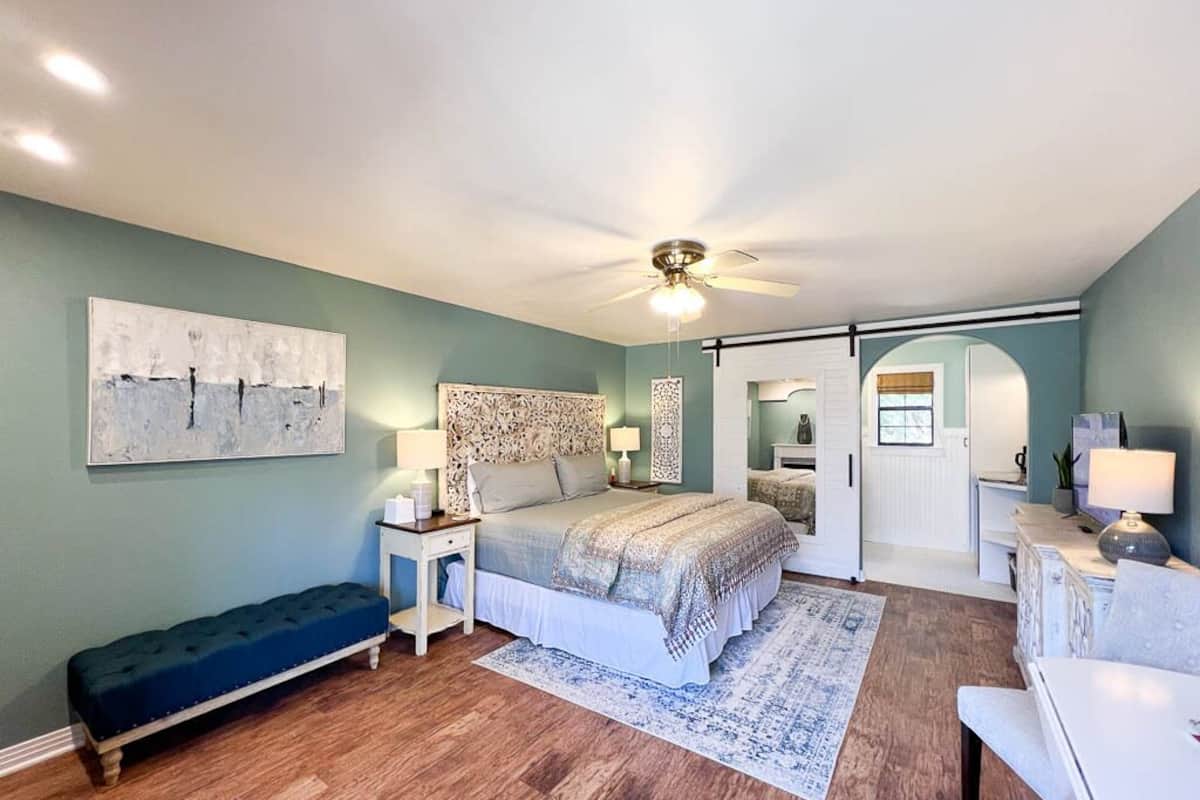 A bedroom with a bed, a bench, a nightstand, a desk, and a chair.
