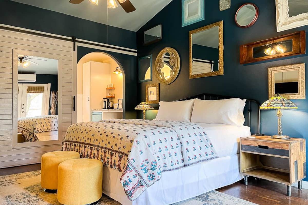 A bedroom with a bed, a nightstand, a mirror, and a wardrobe.