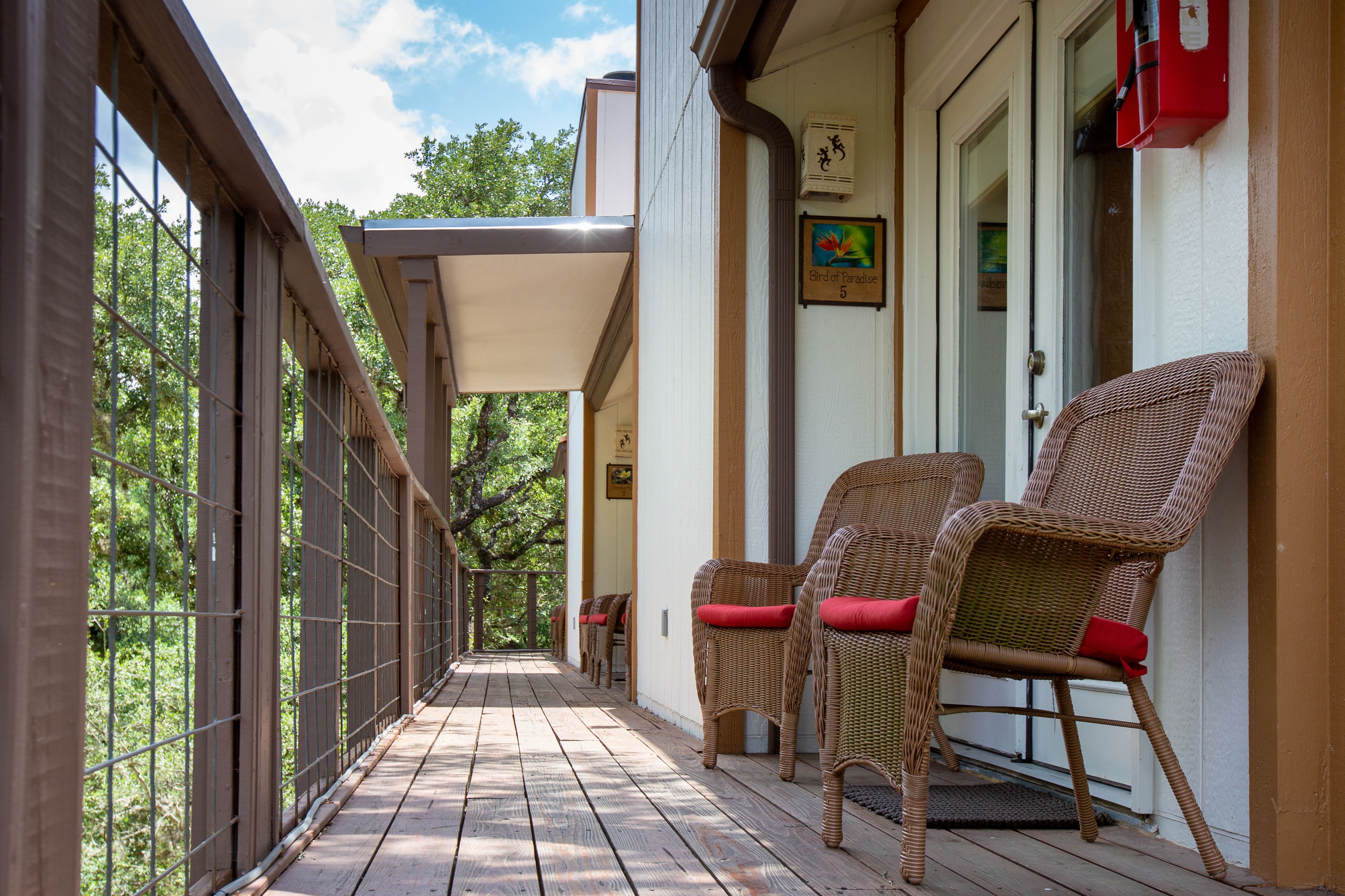 A covered porch with wicker chairs and a door labeled "Bird of Paradise 5".