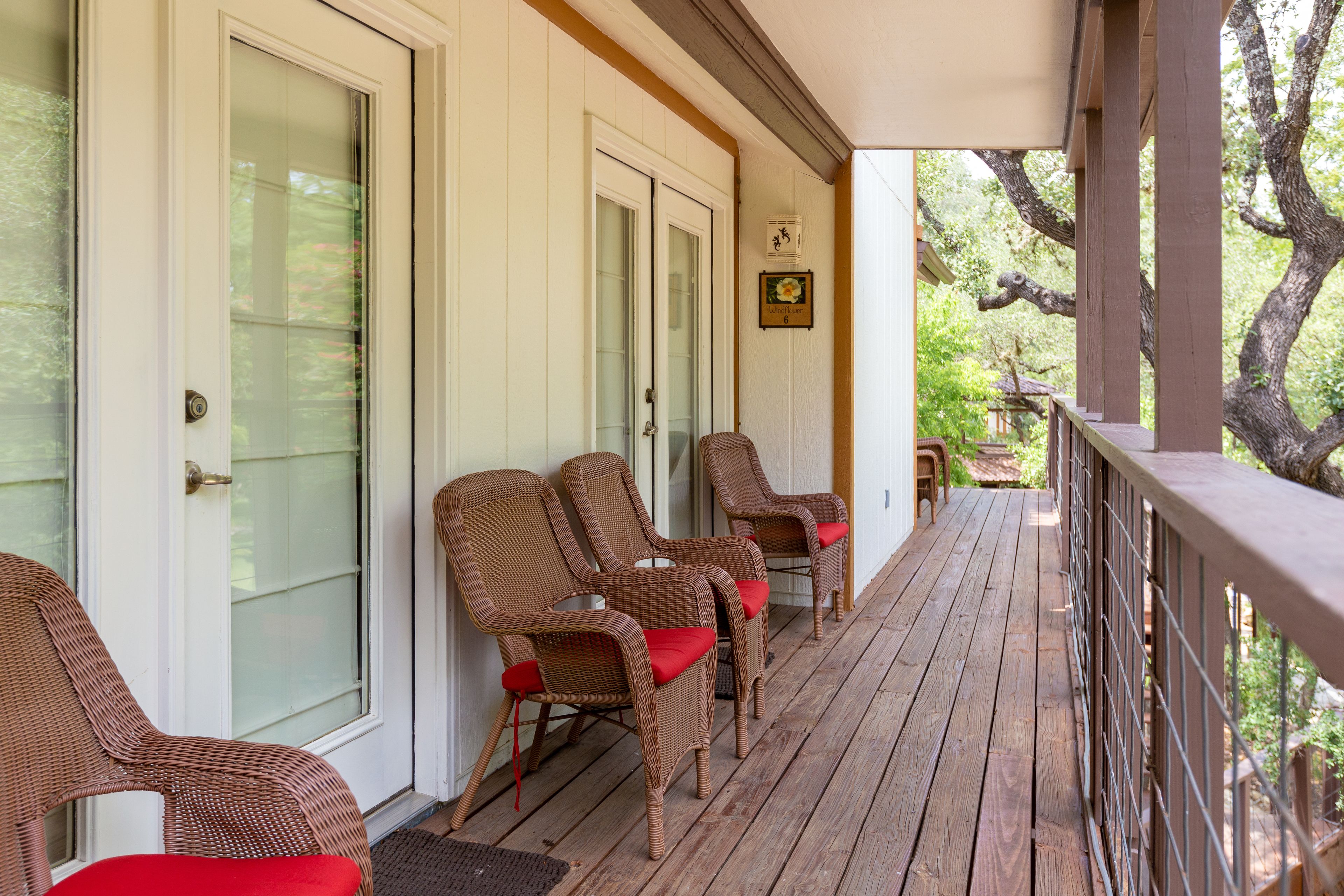 Eine überdachte Veranda mit Korbstühlen und einer Holzterrasse.