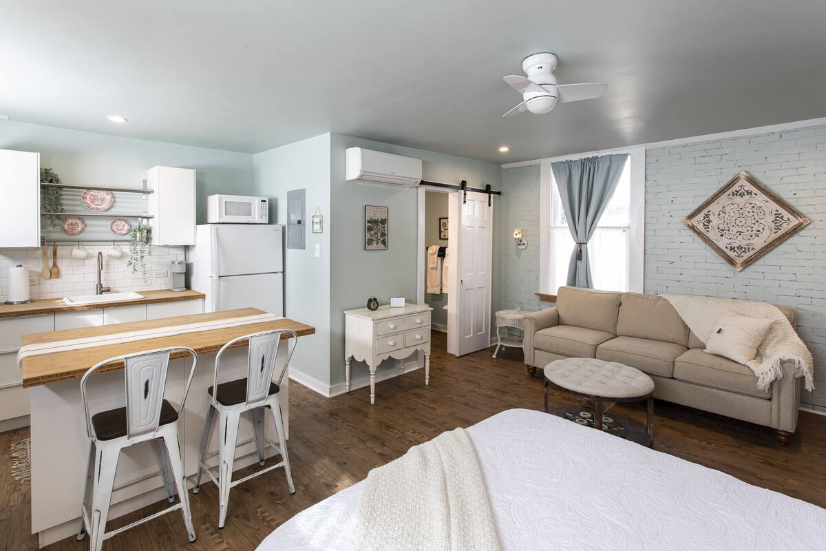 Un espacio habitable compacto con kitchenette, comedor, sofá y cama.