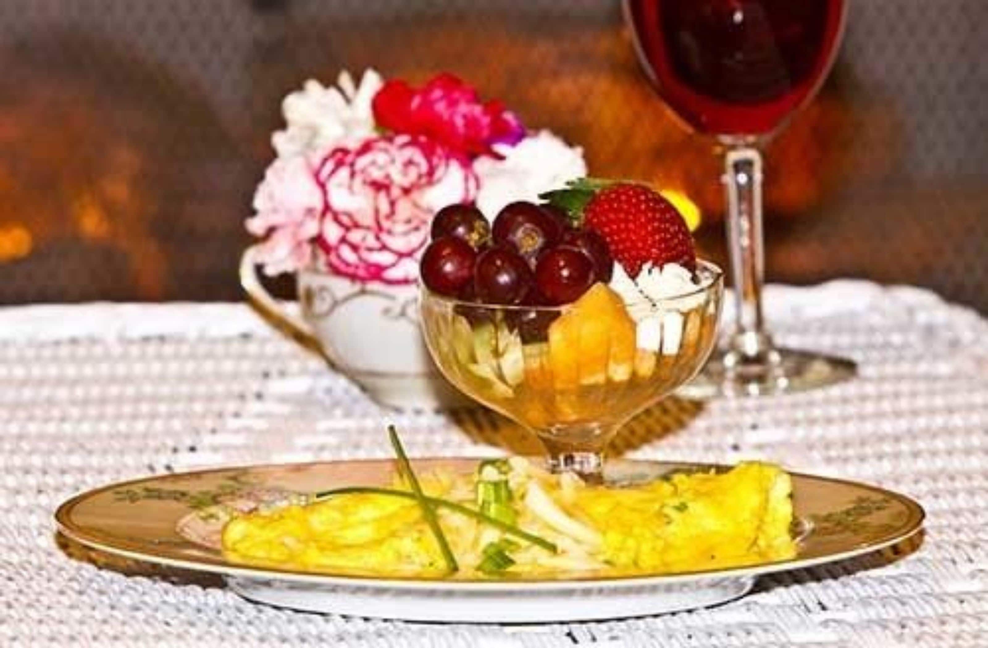 Una tavola da pranzo con una porzione di uova strapazzate e un bicchiere di vino rosso.