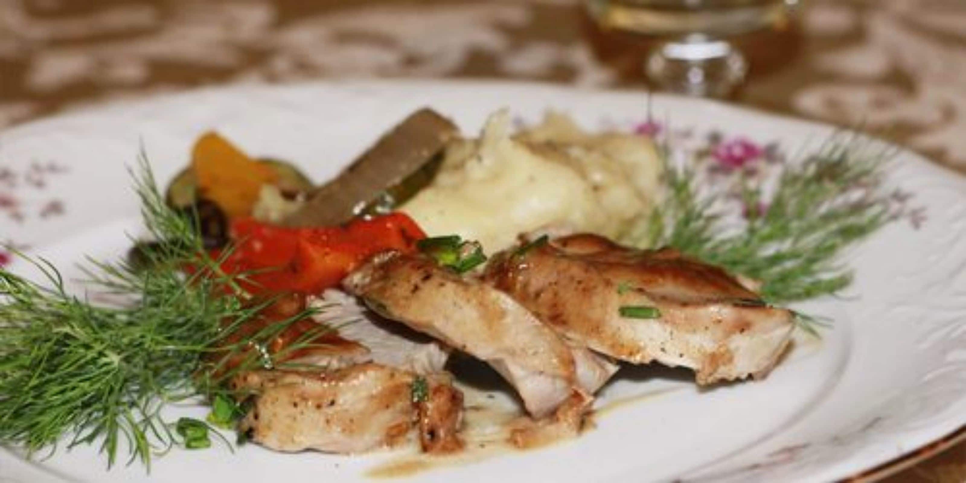 Un plato con pescado a la parrilla, puré de papas y verduras.